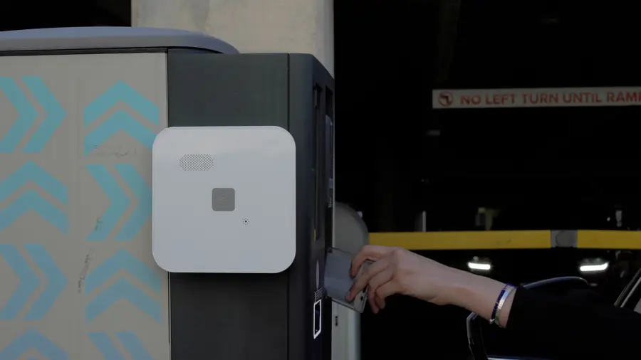 Hand badging an access reader next to an Alarm.com Cell Connector at a garage gate