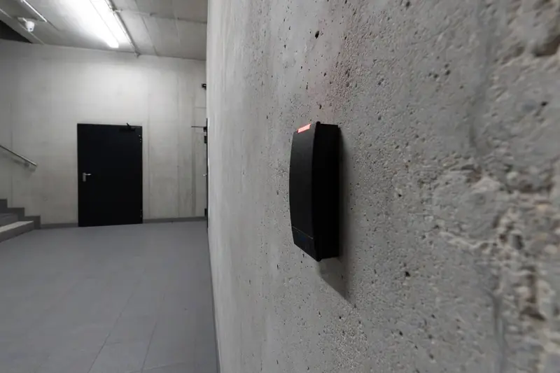 Hallway with a door and an access reader on a concrete wall