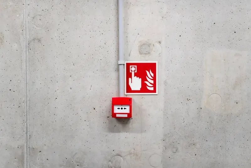 Fire alarm call point and sign on a concrete wall